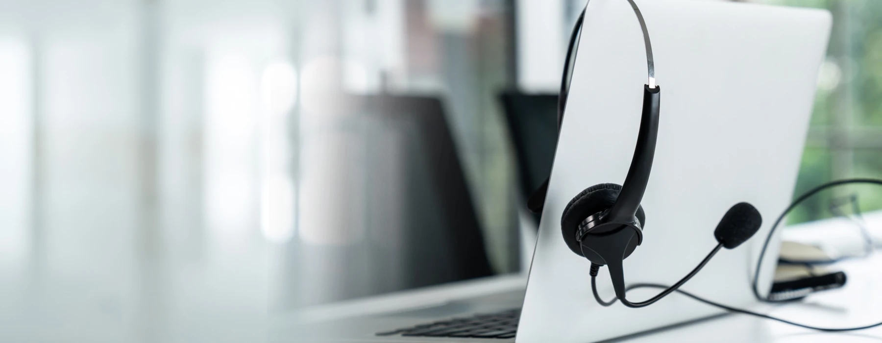 Laptop mit Headset auf einem Schreibtisch – Symbolbild für Kontaktaufnahme und Kundenservice