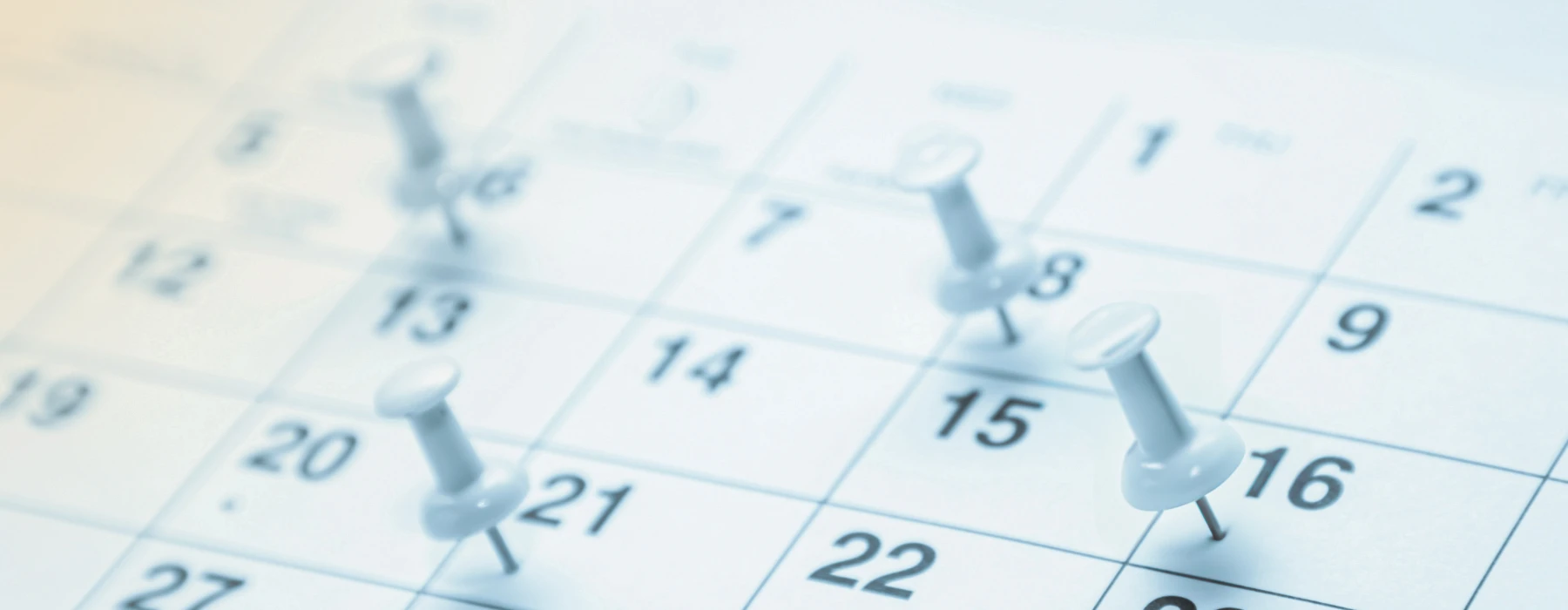 Veranstaltungskalender – Nahaufnahme eines Kalenders mit Pinnnadeln auf verschiedenen Daten, symbolisiert Planung und Terminübersicht für Fortbildungen