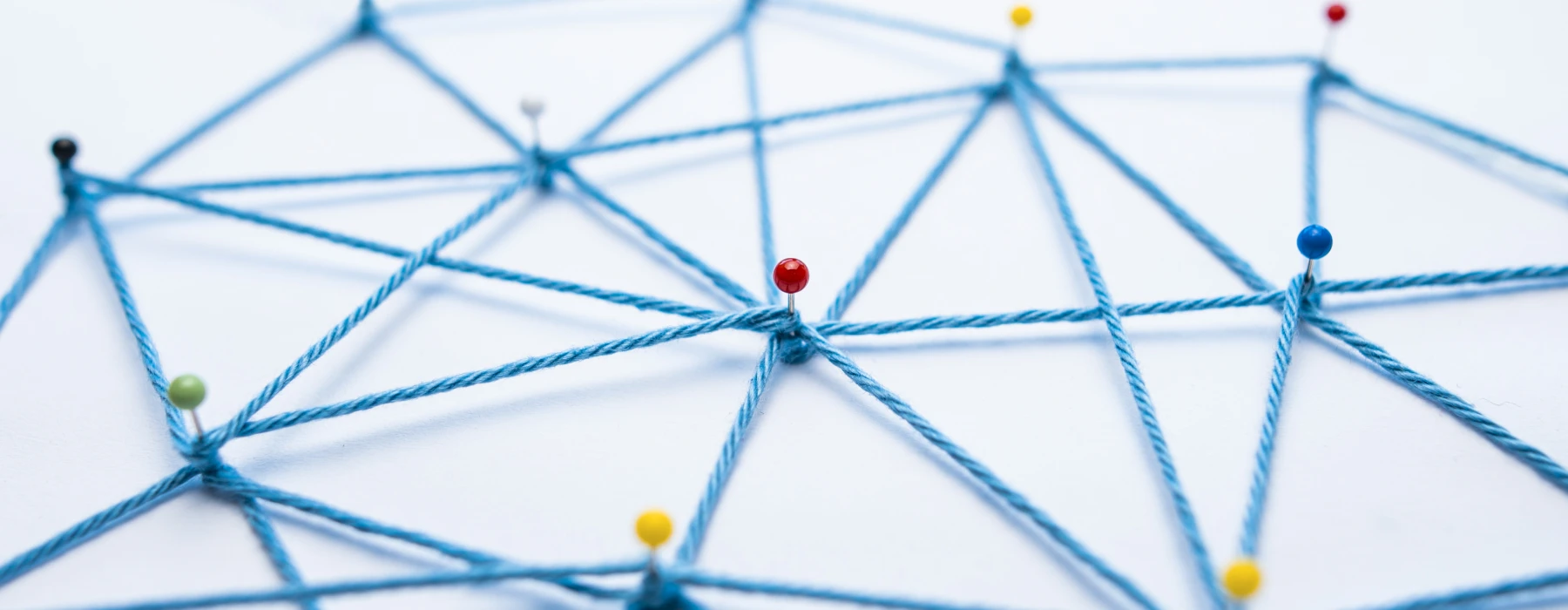 Nonprofit – Vernetzte blaue Fäden mit Pinnadeln als Symbol für gemeinnützige Organisationen, Zusammenarbeit und Netzwerke