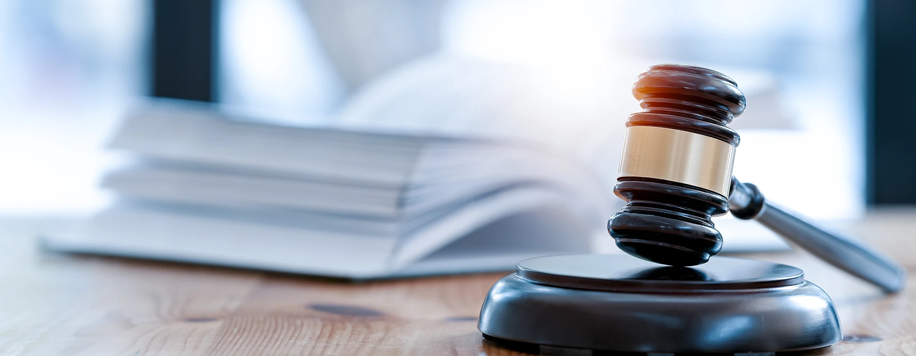 Strafrecht – Richterhammer auf Holztisch mit geöffnetem Gesetzbuch als Symbol für Justiz und Strafverfahren