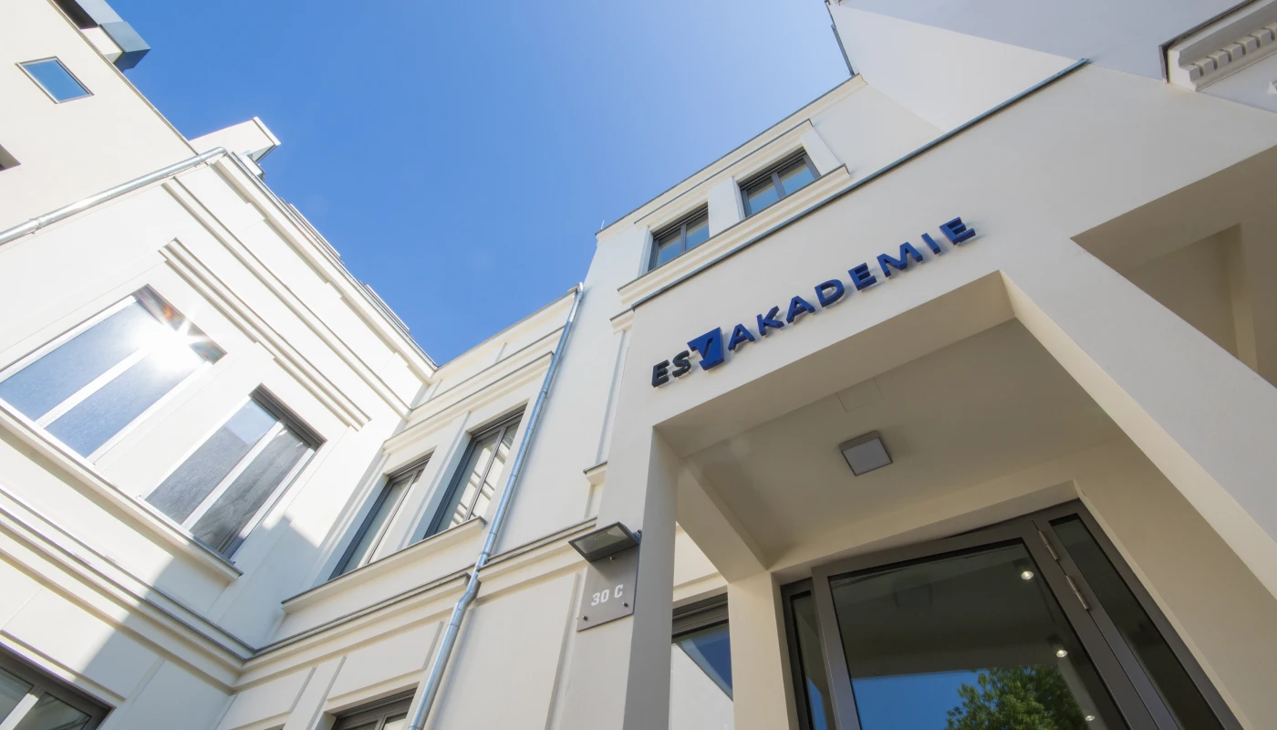 Schräger Blick auf die Außenfassade der ESV-Akademie mit Logo und blauer Himmel im Hintergrund