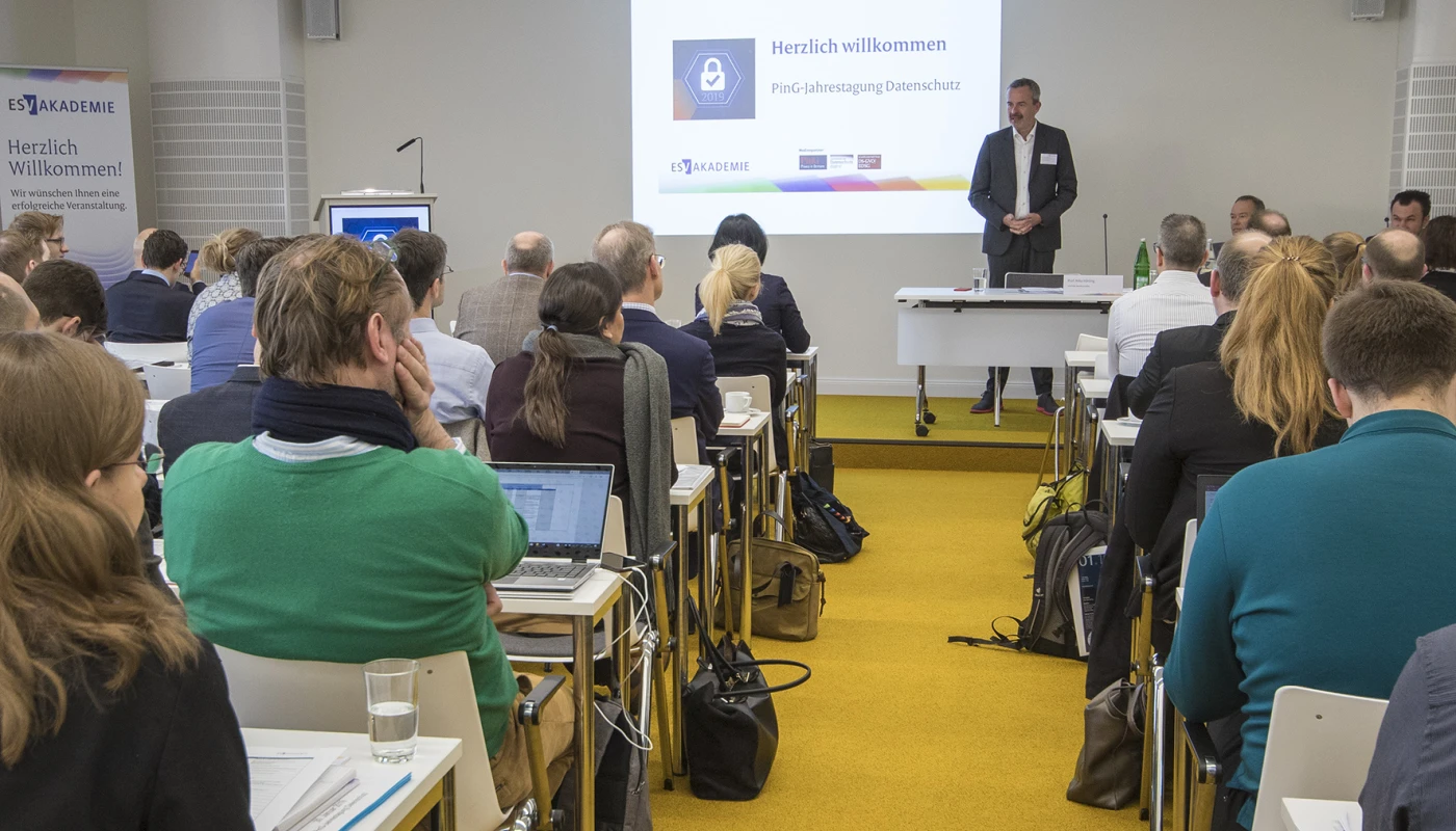 Konferenzsituation mit Publikum in Reihen, Vortrag im Gange