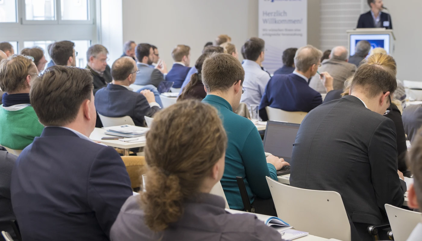 Seminarraum mit Publikum, Sprecher steht an einem Rednerpult