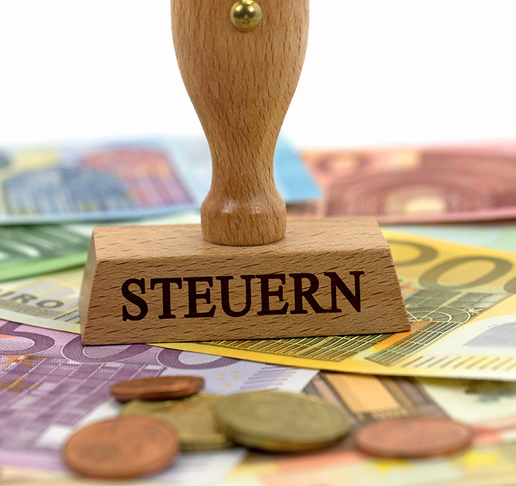 Stempel „Steuern“ auf Euro-Banknoten und Münzen – Symbol für Steuerrecht und öffentliche Abgaben
