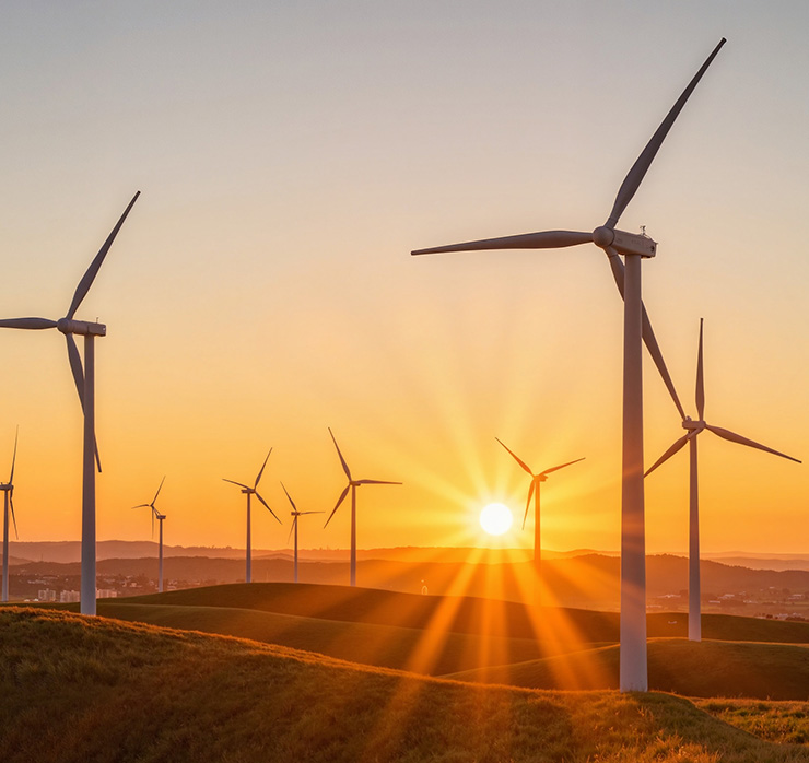 Windpark mit mehreren Windkraftanlagen bei Sonnenaufgang als Symbol für erneuerbare Energien und Stromerzeugung