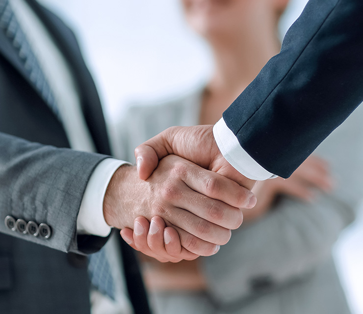 Zwei Personen geben sich die Hand als Symbol für den Erwerb und die Übertragung von Gesellschaftsanteilen im Zusammenhang mit einer Treuhandvereinbarung.