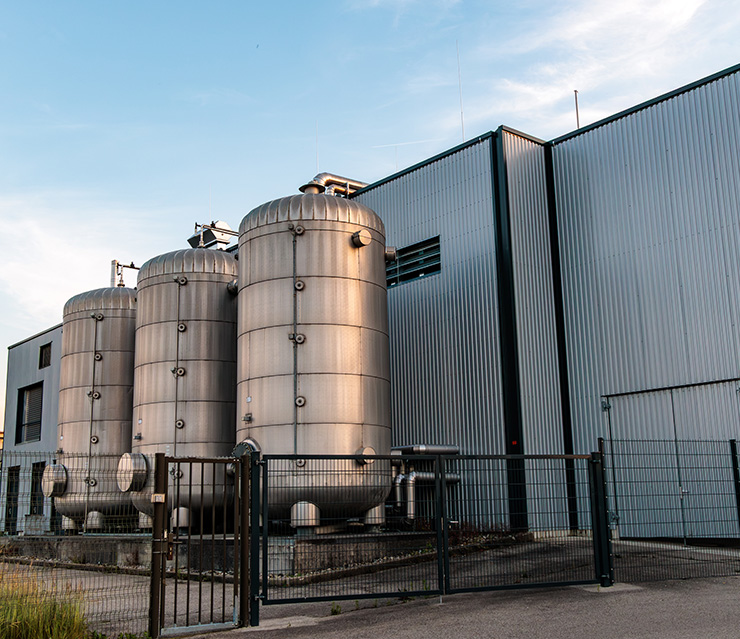 Moderne Energieanlage mit mehreren großen Stahlspeichern und Industriegebäude als Symbol für Kraft-Wärme-Kopplung und Energieversorgung.