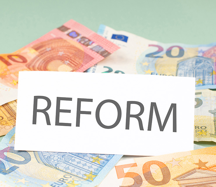 Euro-Banknoten mit einer Karte, auf der „Reform“ steht, als Symbol für geplante Änderungen im Steuer- und Abgabenrecht.